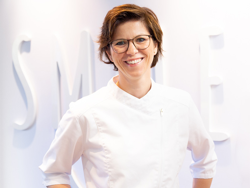 Dr. Moll in ihrer Praxis für Kieferorthopädie in Radolfzell, stehend an der Rezeption in moderner, heller Umgebung.