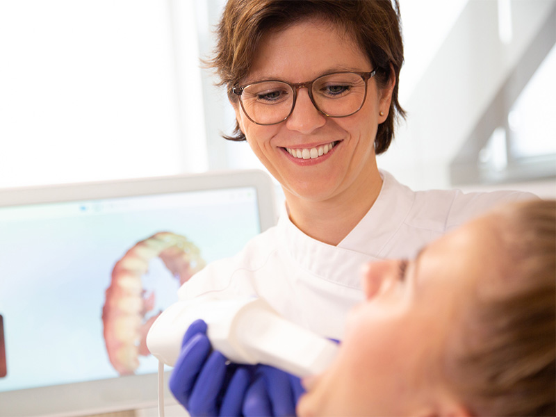 Dr. Moll, Kieferorthopädin in Radolfzell, behandelt eine sitzende Patientin in einem modernen, freundlich eingerichteten Praxisraum.