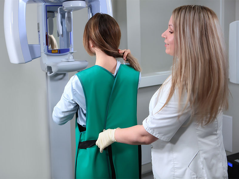 Patientin wird für eine Röntgenaufnahme in der MKG am Bodensee vorbereitet, trägt eine Schutzweste.