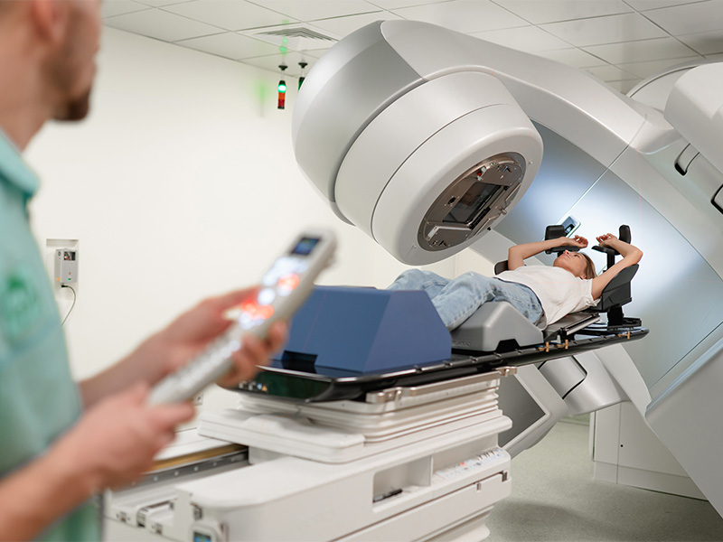 Patient liegt bei einer Bestrahlung in Konstanz auf einem Linearbeschleuniger, während medizinisches Fachpersonal die Behandlung überwacht